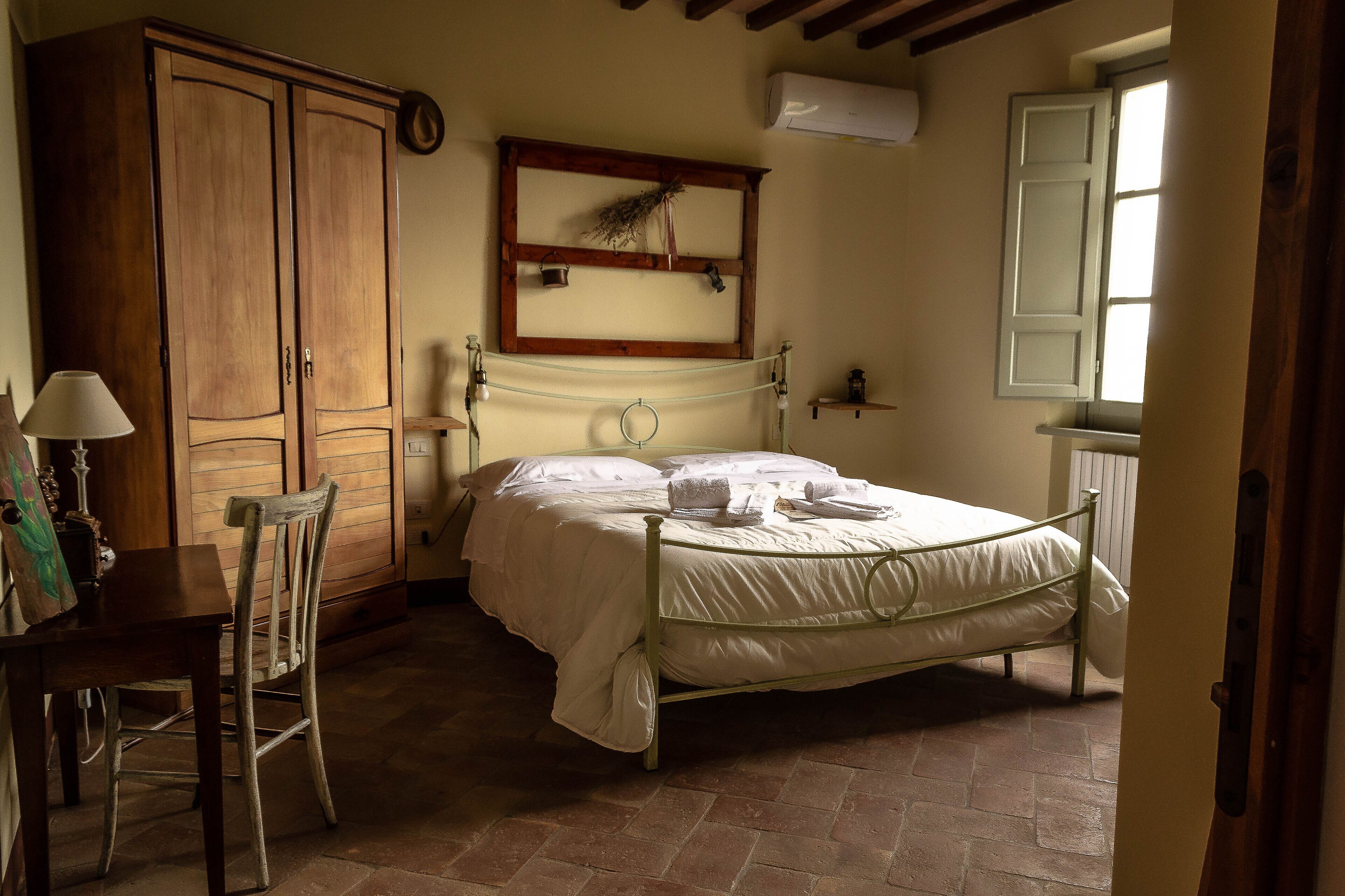 Une chambre à coucher avec un lit, une armoire en bois et une petite table avec une chaise.