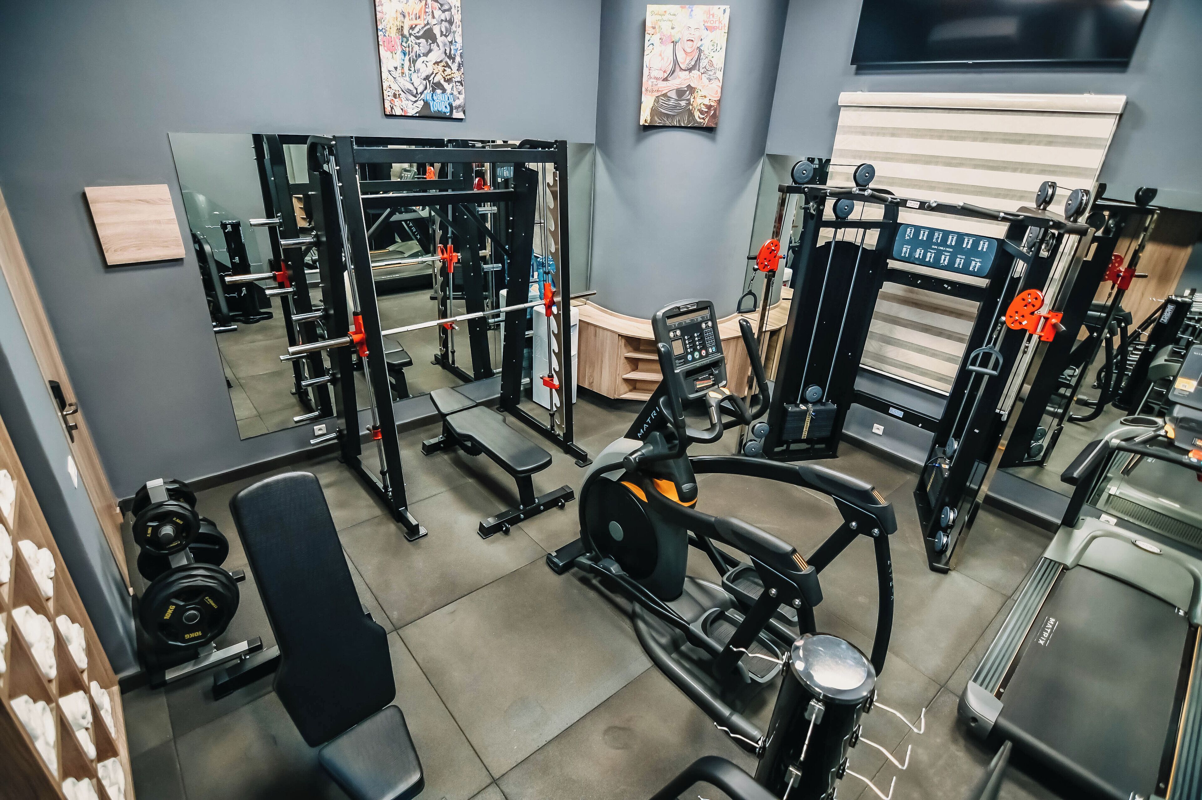 A gym with various exercise equipment, including a treadmill, weight machines, and a bench.