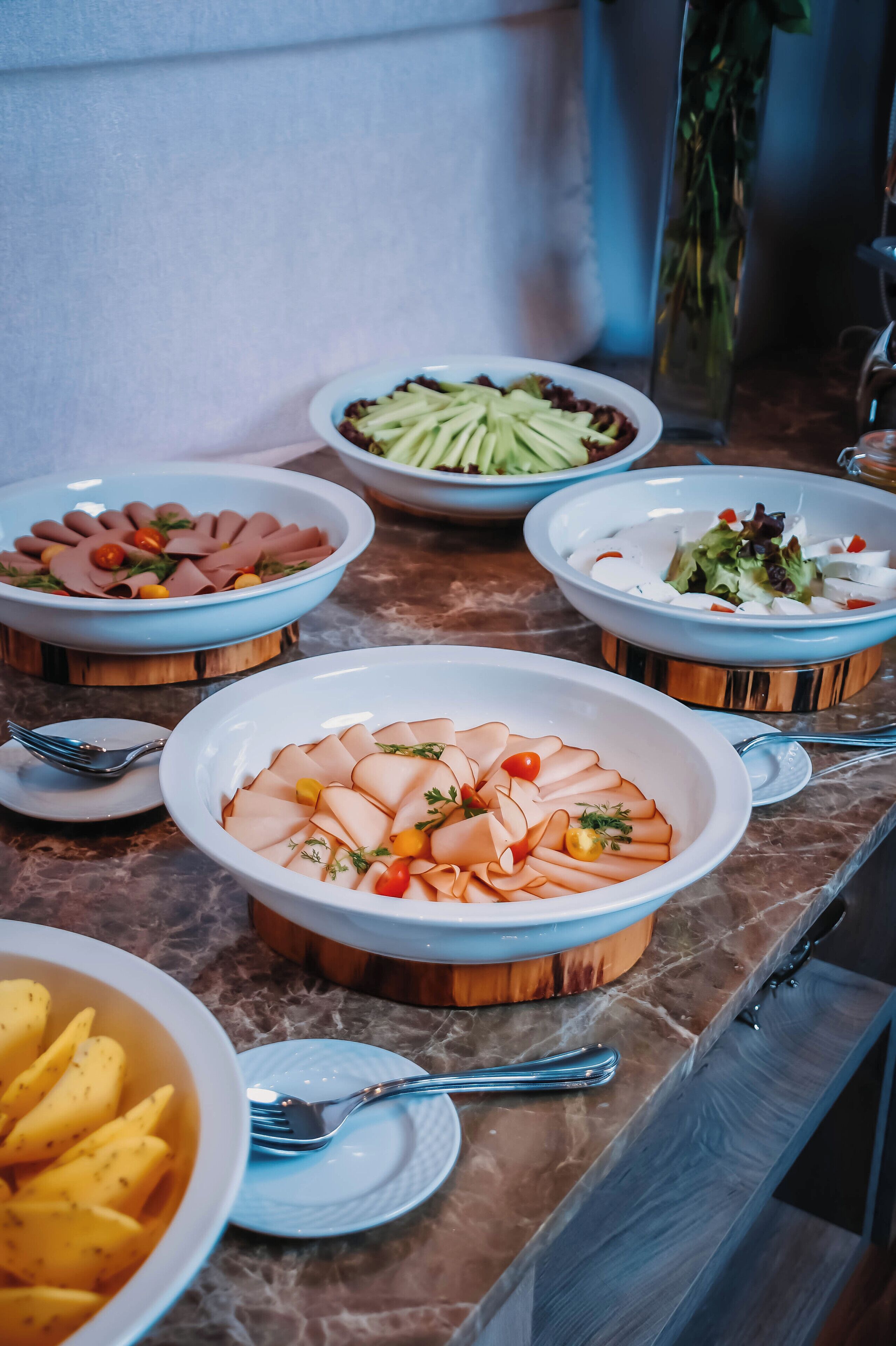 A buffet table with various dishes including sliced meats, vegetables, and salads.