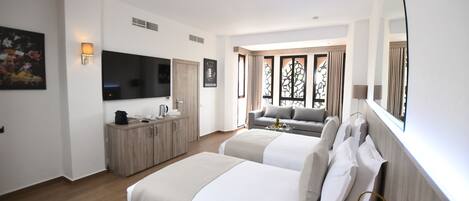 A hotel room with two beds, a TV, a desk with a lamp, and a window with curtains.