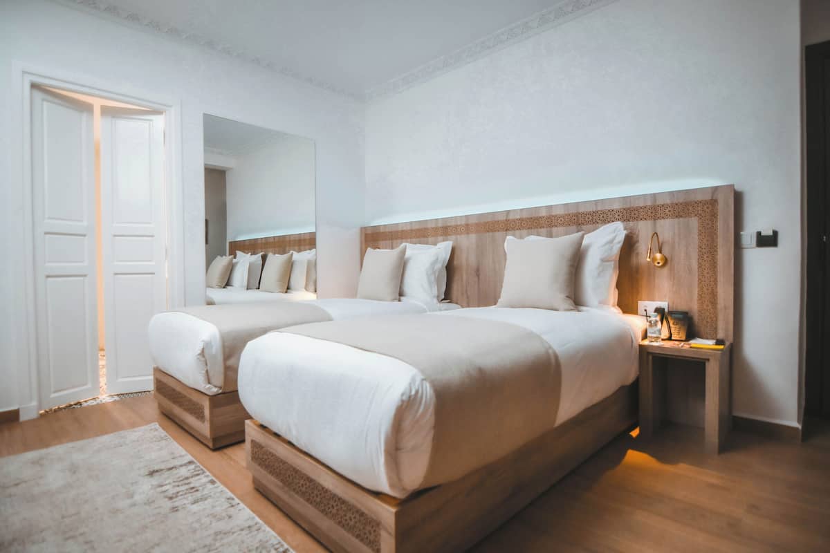 A double bed with a wooden headboard, a bedside table with a lamp, and a white door.