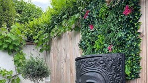A garden with a stone sculpture, a tall planter, and a wooden fence. - Charmante Maison, Piscine, Spacieuse, 5 mn Aix (Aix-en-Provence)