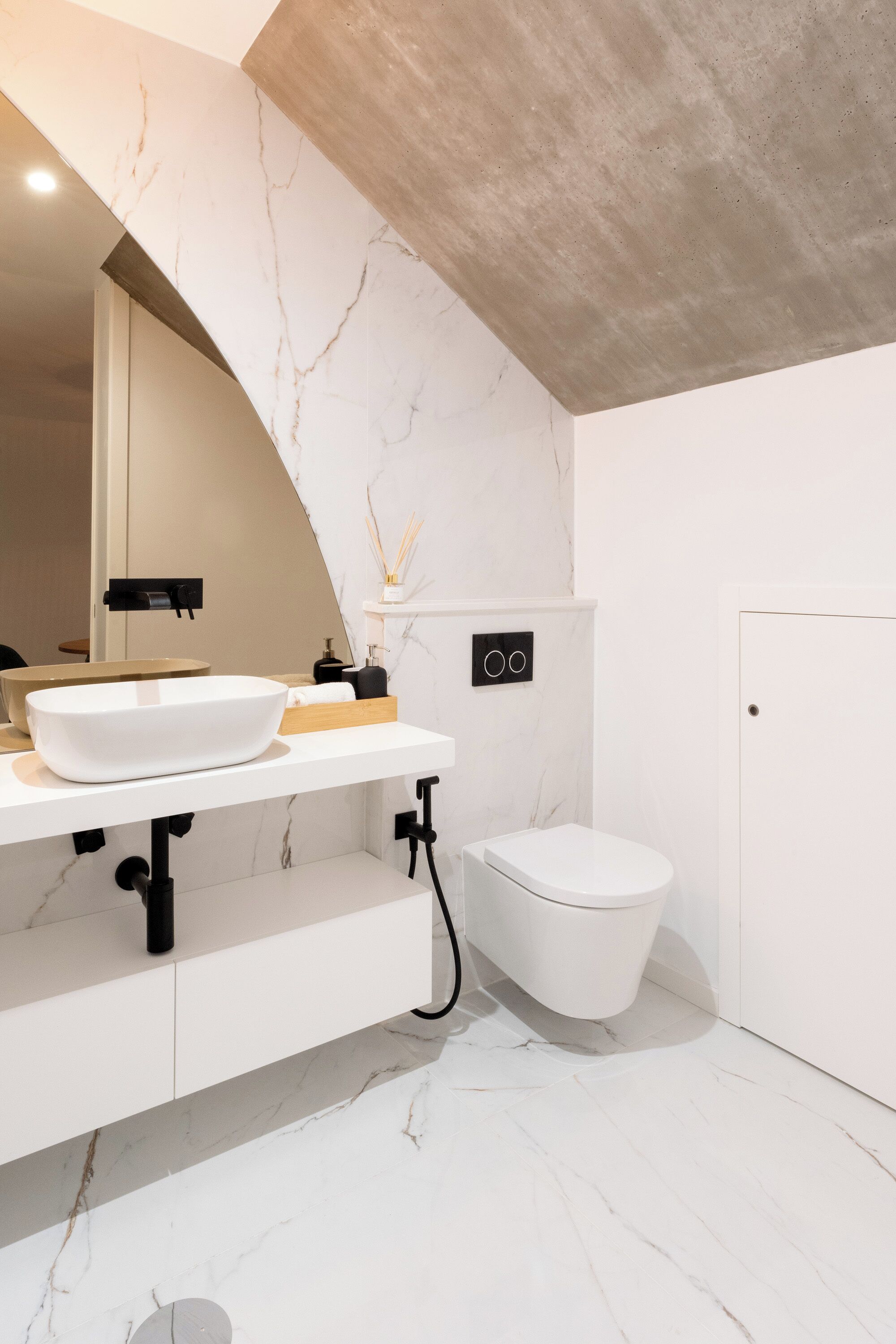 A modern bathroom with a white marble sink, a toilet, and a shower area.