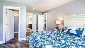 Ein Schlafzimmer mit einem großen Bett, einem Nachttisch und einer Kommode. Es gibt zwei Türen zu anderen Räumen.