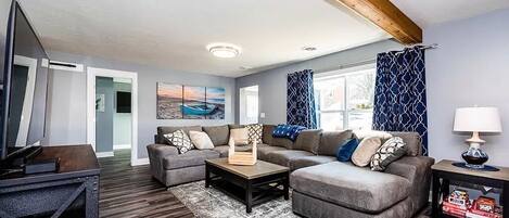 A modern living room with a sectional sofa, a coffee table, and a TV on a wooden stand.