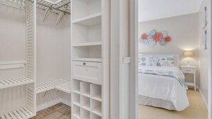 Une chambre à coucher comprenant un lit, une table de chevet et une armoire blanche dotée de plusieurs étagères et de tiroirs.