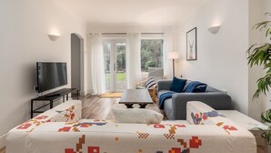 Un salon moderne avec un canapé, un téléviseur et un tapis à motifs.