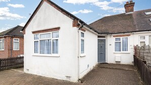 Une maison de plain-pied à l’extérieur blanc, avec une cheminée en briques et le numéro « 39 » peint sur le mur.