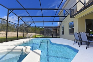 Une piscine dotée d’un patio couvert, d’un espace salon extérieur et offrant une vue sur une maison.