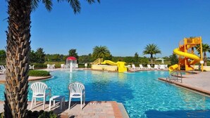 Una piscina con toboganes, sillas de descanso y palmeras.