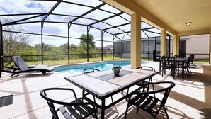 Un espacio al aire libre cubierto con piscina, sillas de descanso y una mesa con sillas.