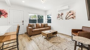 Ein modernes Wohnzimmer mit einer braunen Ledersofa, einem Holztisch und einem Essbereich mit Holztisch und Stühlen.