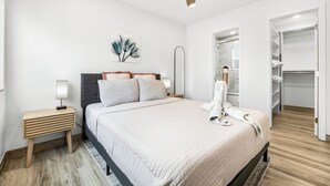 Ein modernes Schlafzimmer mit Bett, Nachttischen, Deckenventilator, Kleiderschrank und Spiegel.