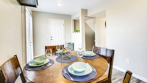 Comedor con mesa de madera dispuesta para cuatro, incluyendo platos, tazones y cubiertos.
