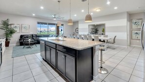 Una cocina moderna con una isla grande, luces colgantes y una zona de comedor con vistas.
