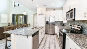 A modern kitchen with granite countertops, stainless steel appliances, and white cabinetry.