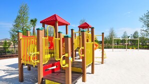 Un parque infantil con un tobogán, estructuras para escalar y una casita de techo rojo.