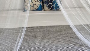 A room with a canopy bed, wooden walls, and framed artwork. - Turtle Hideaway is close to Beach in Silversands, Barbados only a 3 minute walk. (Silver sands)