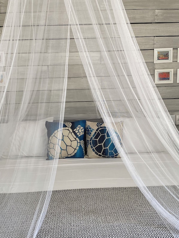 A room with a canopy bed, wooden walls, and framed artwork. - Turtle Hideaway is close to Beach in Silversands, Barbados only a 3 minute walk. (Silver sands)
