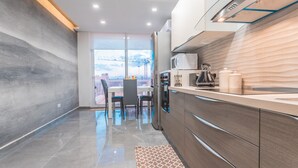 A modern kitchen with a large window, a dining area with chairs, and a view of a bridge.