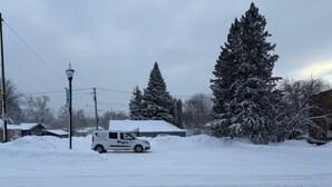 Una calle cubierta de nieve con una camioneta blanca estacionada frente a un edificio.