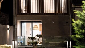 A modern building with a glass entrance, a balcony, and a well-maintained garden.