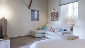 A modern bedroom with a bed, a sofa, a small table, and artwork on the walls. - PM2        (Castello Cabiaglio)
