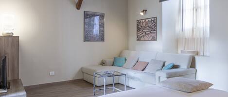 Une chambre à coucher moderne avec un lit, un canapé, une petite table et des œuvres d’art accrochées aux murs.