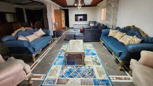 Ein geräumiges Wohnzimmer mit zwei blauen Sofas, einem Couchtisch und einem Fernseher.