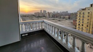 Ein Balkon mit Blick auf eine Stadtlandschaft bei Sonnenuntergang.