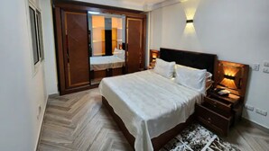 Ein Schlafzimmer mit einem Bett, Nachttischen, einem Kleiderschrank und einem Spiegel.