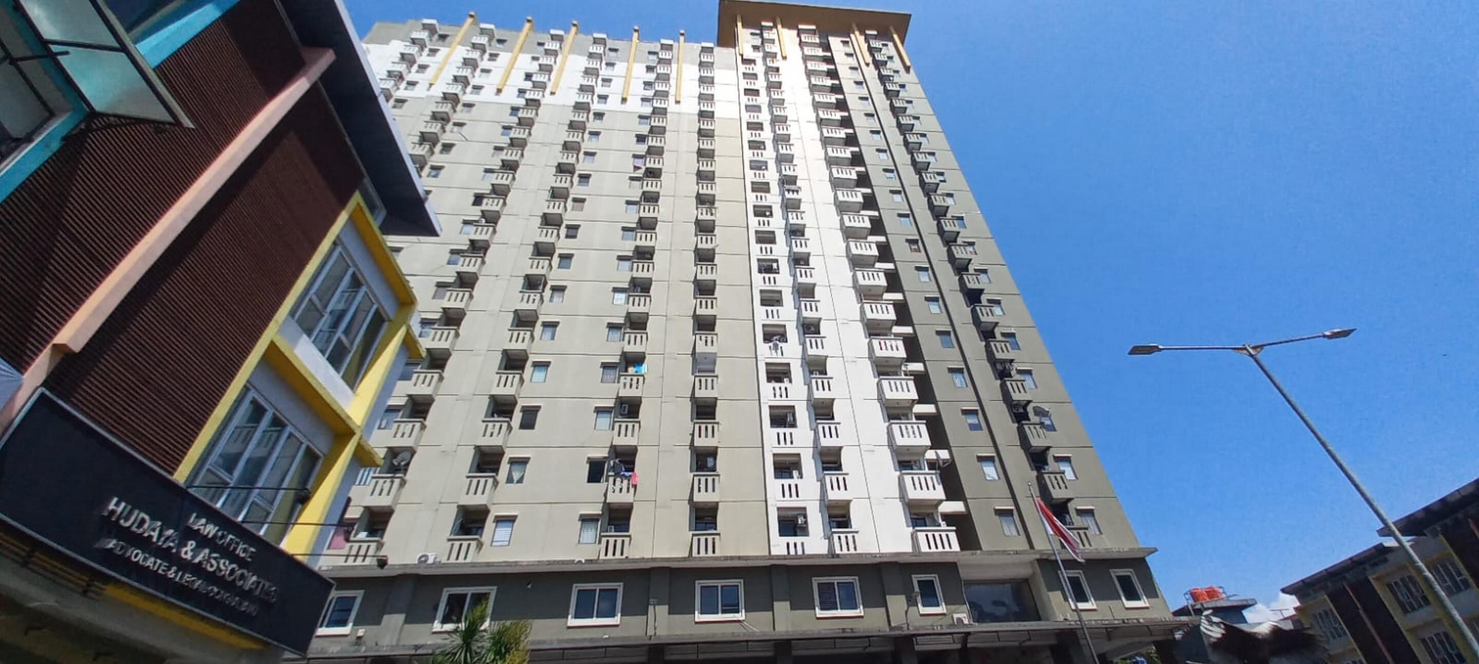 A high-rise building with multiple balconies and a clear blue sky.