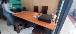 Une pièce avec une table en bois, une mallette noire, un carnet et un stylo. Il y a une chaise et un tabouret près de la table.