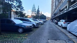 A row of parked cars along a paved sidewalk in an urban area. - OYO 93480 Apartement Gateway Cicadas By Kelola Room (Bandung)