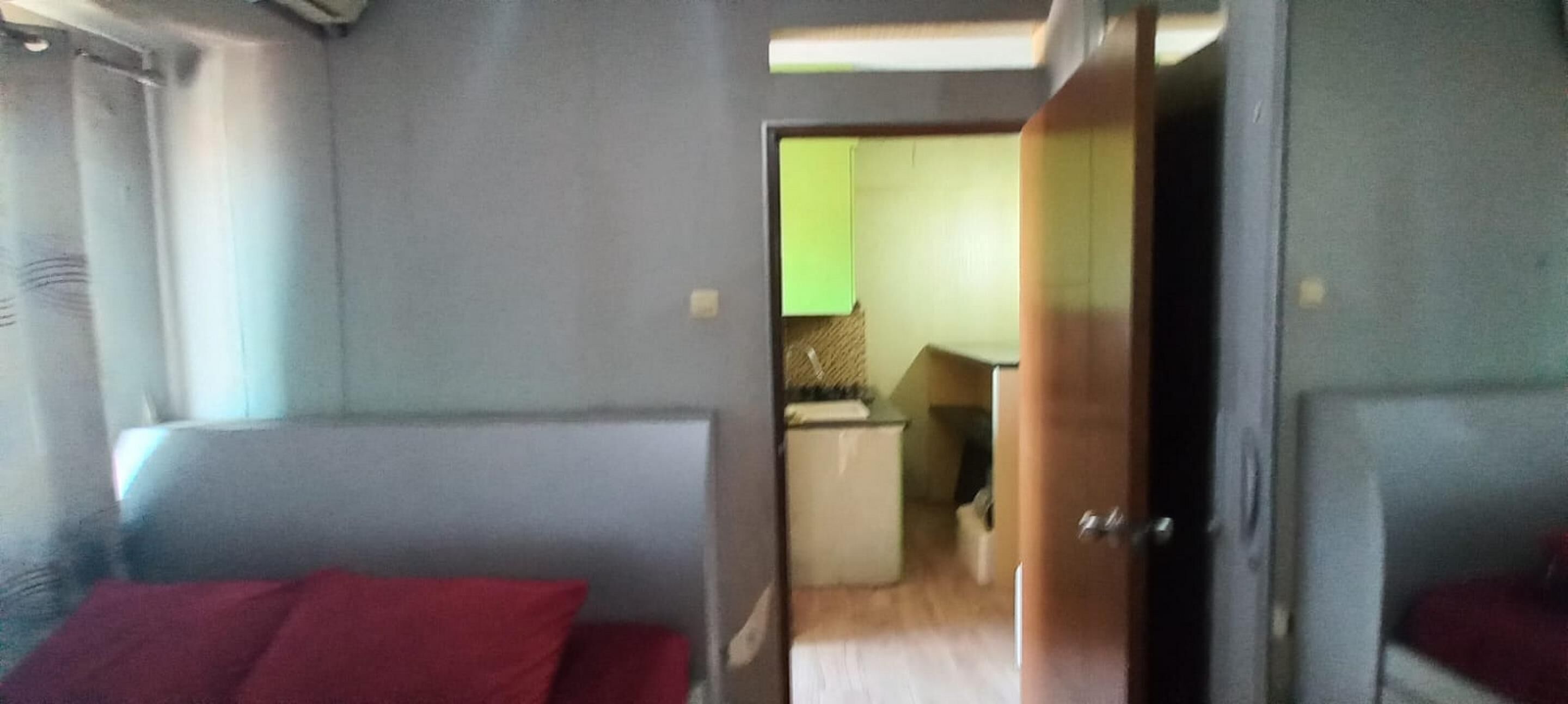 A compact room with a bed, a small kitchenette, and a bathroom.
