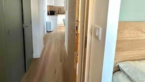 A narrow hallway with wooden flooring leading to a kitchen area. - Appartement T2 - Proche Centre et Lac (Aix-les-Bains)