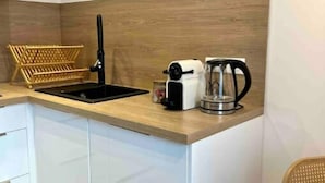 A compact kitchen with a wooden countertop, a black faucet, a coffee maker, and a wicker basket. - Appartement T2 - Proche Centre et Lac (Aix-les-Bains)