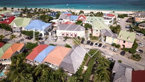An aerial view of a coastal town with colorful buildings, a beach, and a clear view of the ocean.
