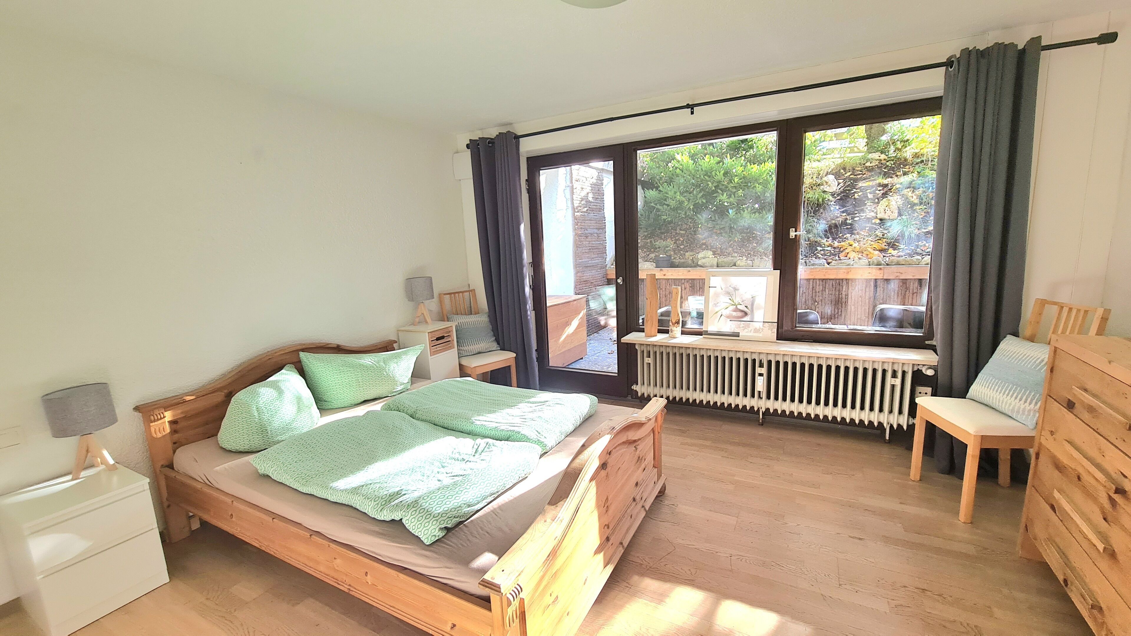Un dormitorio con una cama de madera, un escritorio, una silla y vistas a un balcón.