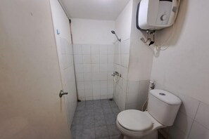 Un baño pequeño y funcional con inodoro, ducha y calentador de agua instalado en la pared.