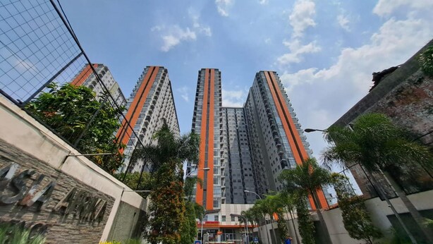 A high-rise building with multiple floors, surrounded by greenery and a clear sky. - Capital O 93481 Apartement Grand Asia Afrika By Kelola Room (Bandung)
