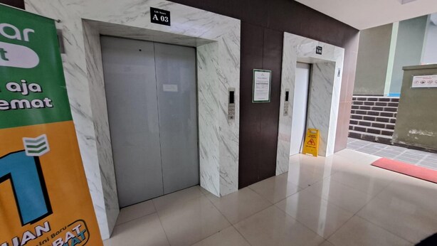 A hallway with marble walls and a sign indicating room A03. - Capital O 93481 Apartement Grand Asia Afrika By Kelola Room (Bandung)