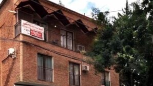 Ein Backsteinhaus mit Schaufenster, davor ein rotes Lieferfahrzeug und ein Verbotsschild.