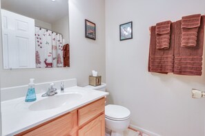 Ein Badezimmer mit weißem Waschbecken, Holzschrank, Toilette in Weiß und zwei gerahmten Bildern an der Wand.