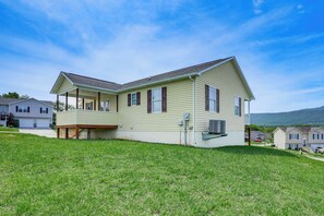 Ein zweistöckiges Haus mit überdachter Veranda und kleiner Terrasse.