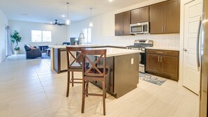 A modern kitchen with a large island, dark wooden cabinets, stainless steel appliances, and a view to the living area. - Spacious Maricopa Vacation Home ~ 4 Mi to Downtown (Maricopa)