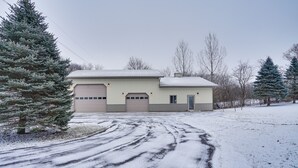 A two-story house with a garage, a driveway, and snow-covered ground. - Peaceful Ellsworth Vacation Rental w/ Grill (Ellsworth)