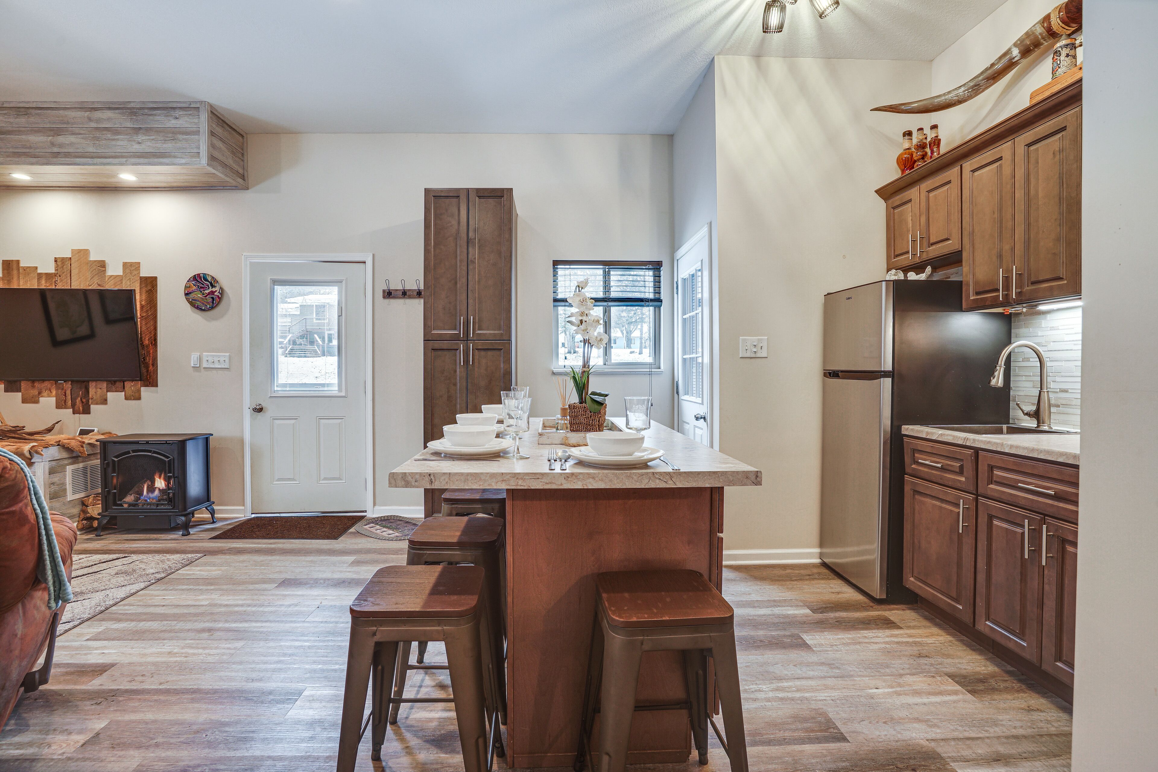 Een moderne keuken met een groot eiland, houten keukenkastjes en een ingebouwde kookplaat.