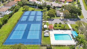 An aerial view of a residential area with a large tennis court and a swimming pool. - CASA BELLA - HEATED POOL- HOT TUB- POOL TABLE -BBQ-PEACEFUL OASIS- 4 BEDS-  (Boynton Beach)