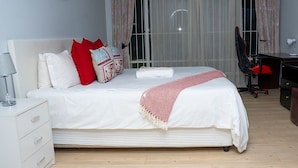Une chambre bien rangée, avec un lit, un bureau et une chaise.
